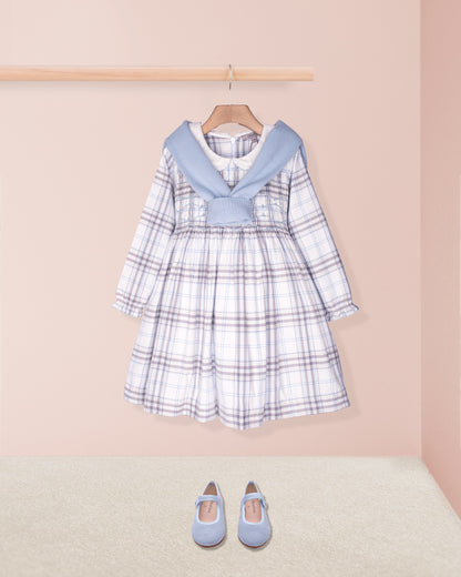 Children's plaid dress with blue collar and matching shoes on a pink background