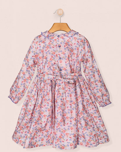 Floral dress on a hanger against a light pink background