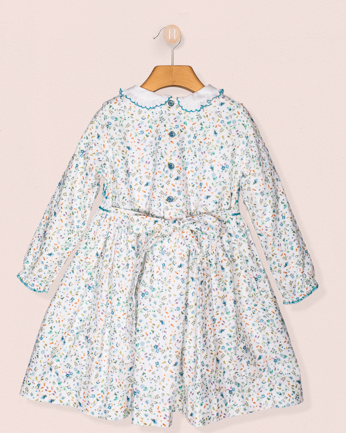 Floral dress on a hanger against a light pink background