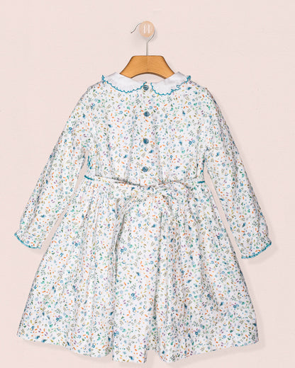 Floral dress on a hanger against a light pink background