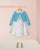 Children's outfit with floral dress and blue cardigan on a pink background