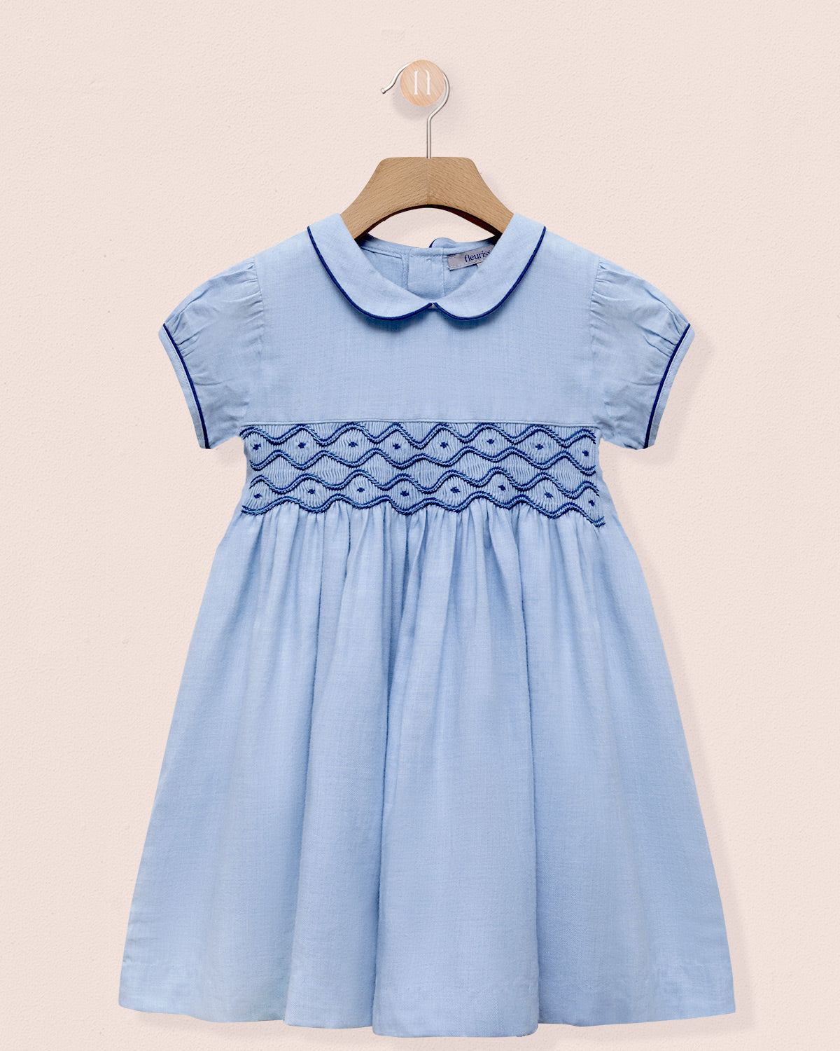 Light blue dress with embroidered details on a beige background