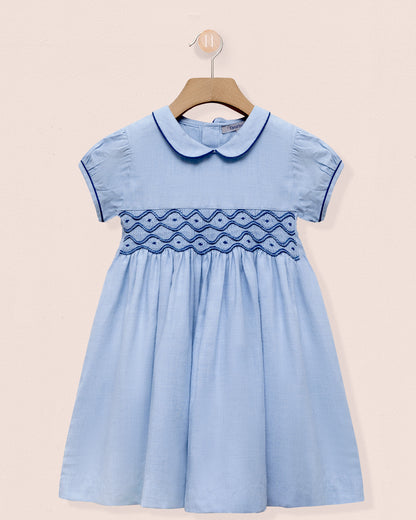 Light blue dress with embroidered details on a beige background