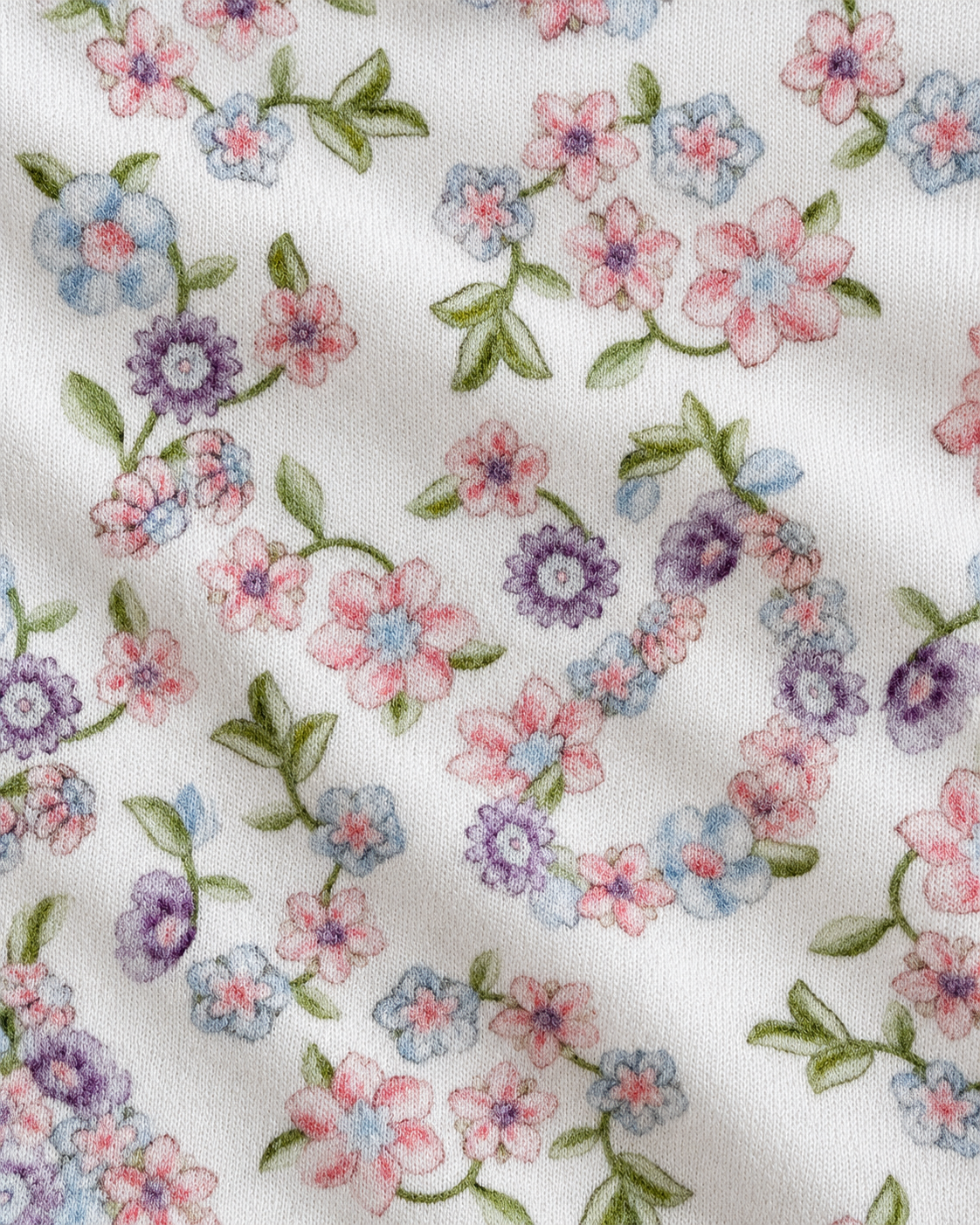 Close-up of a white fabric with a delicate floral pattern featuring pink, purple, and light blue flowers with green leaves.