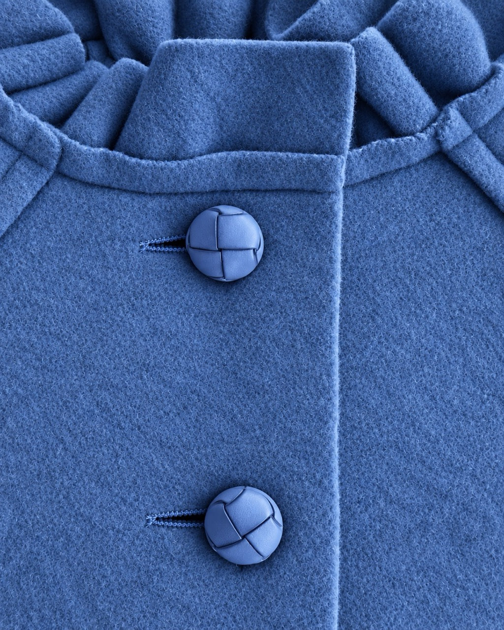 Closeup of blue coat showing 2 top vertical buttons and ruffled neckline