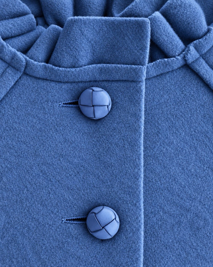 Closeup of blue coat showing 2 top vertical buttons and ruffled neckline