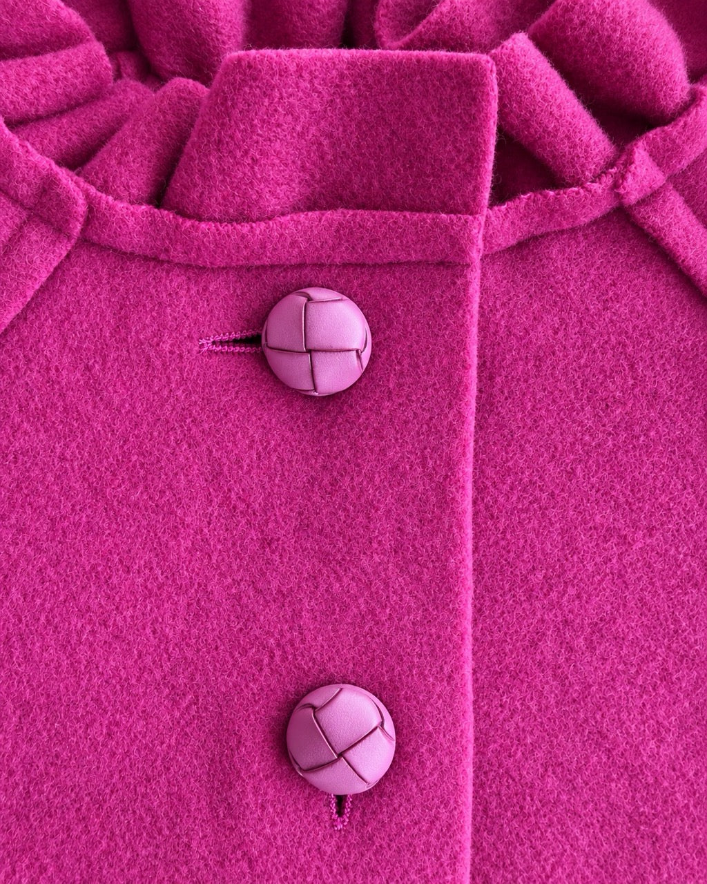 Closeup of a redish purple coat showing 2 buttons and collar