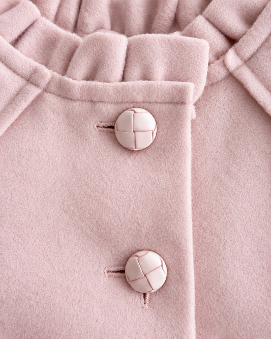 Close up of a light pink colored coat showing 2 top buttons and neckline
