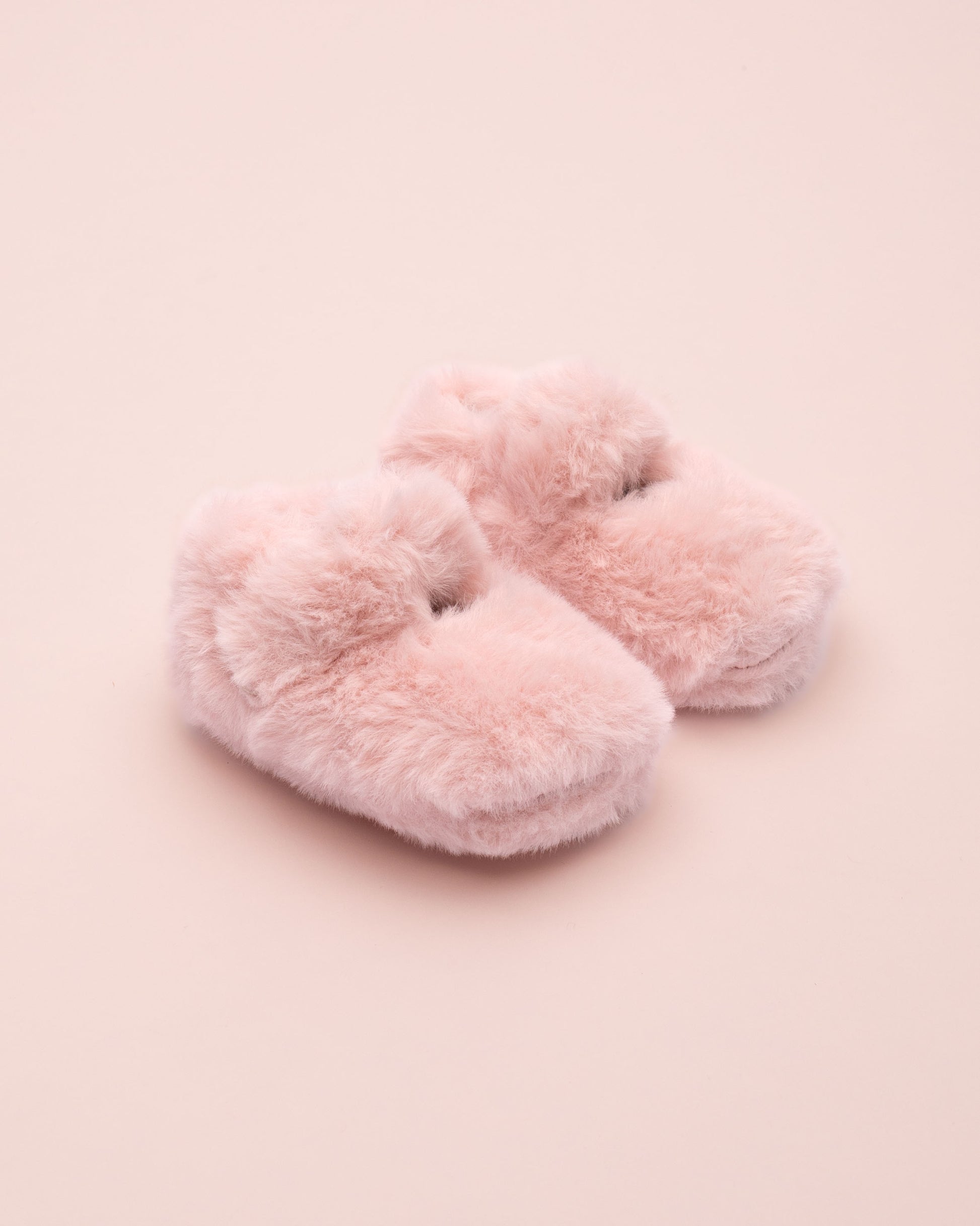 Pair of pink fluffy crib shoe on a pink background