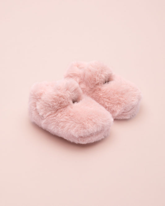 Pair of pink fluffy crib shoe on a pink background