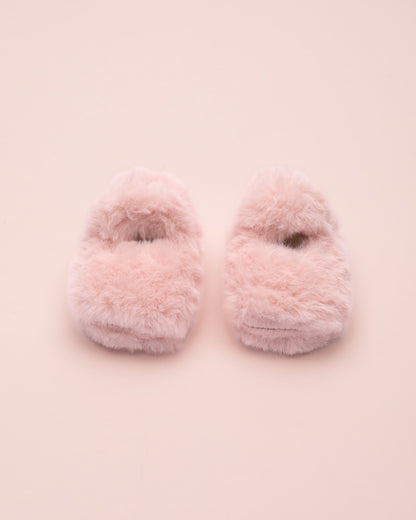 Pair of pink fuzzy crib shoe on a light pink background