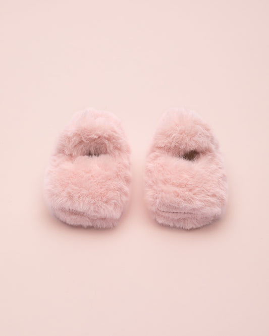 Pair of pink fuzzy crib shoe on a light pink background