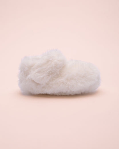 White fluffy crib shoe side view on a light pink background