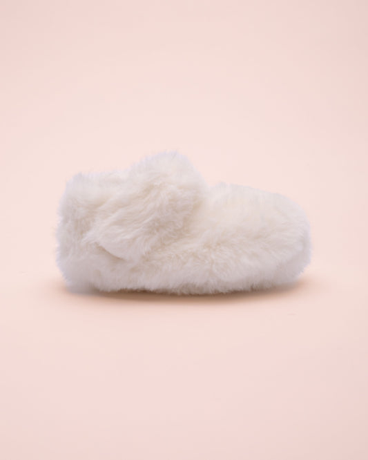 White fluffy crib shoe side view on a light pink background