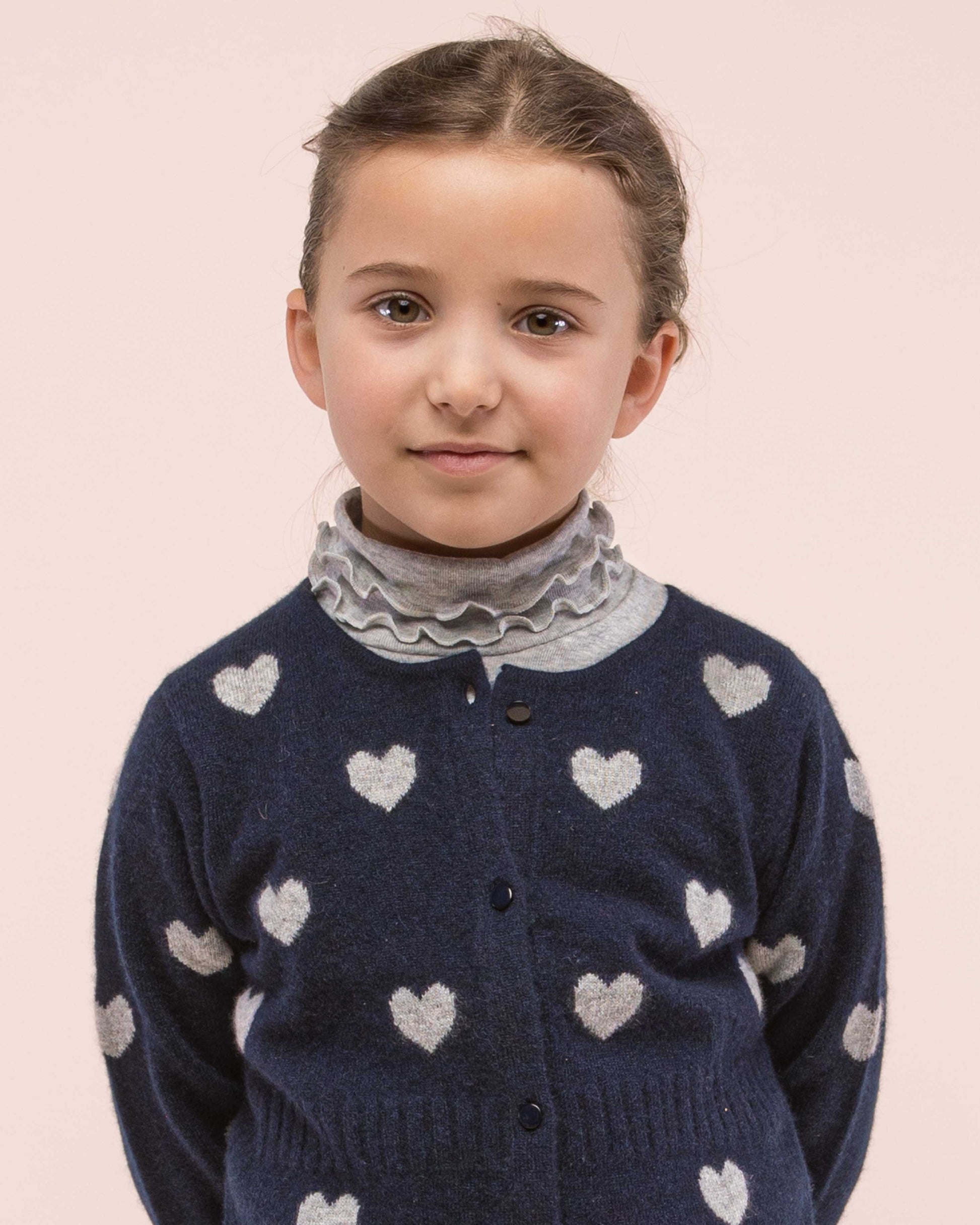 Girl model wearing Grey ruffle turtleneck with a coordinating Cashmere sweater in a contrasting color showing the ruffle details on the turtleneck 