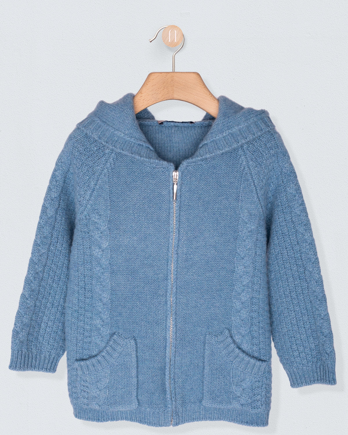 Blue knitted hoodie with a zipper on a wooden hanger against a light gray background