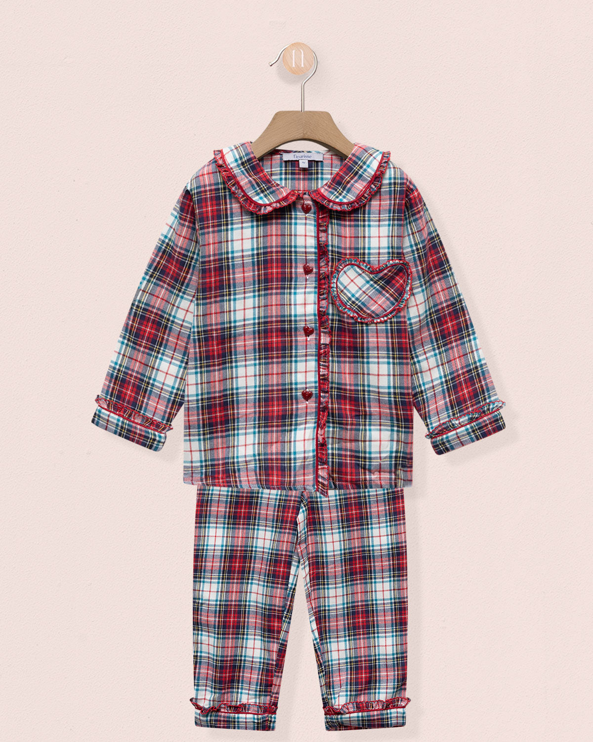 Plaid pajama set on a hanger against a light pink background