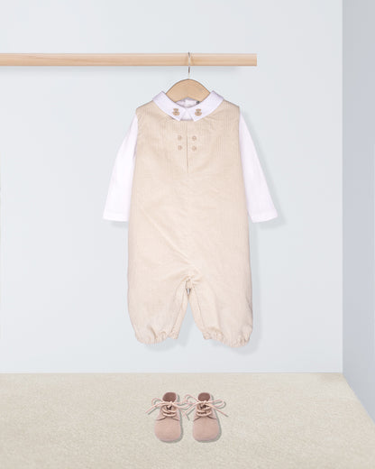 Beige baby romper with white shirt and pink shoes on a light gray background