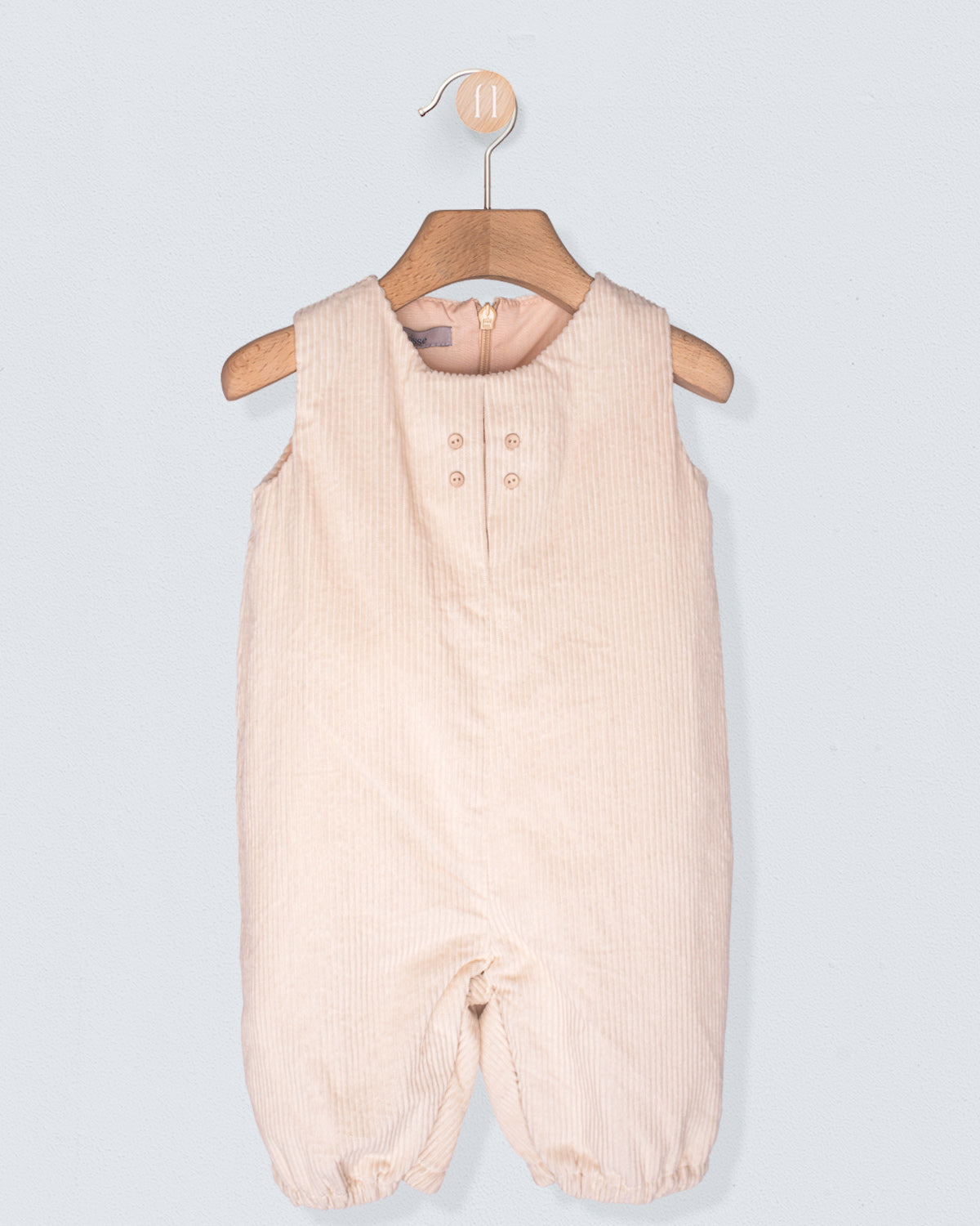 Beige baby romper on a hanger against a light gray background