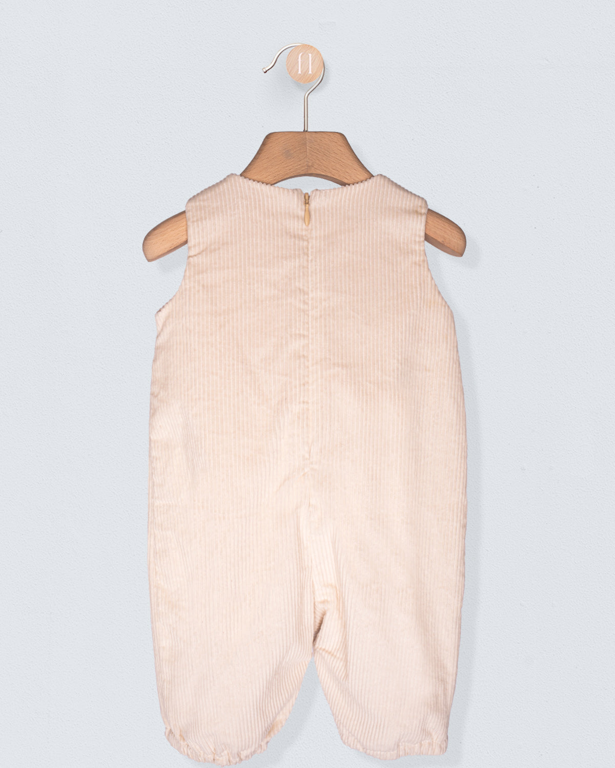 Beige baby romper on a hanger against a light gray background