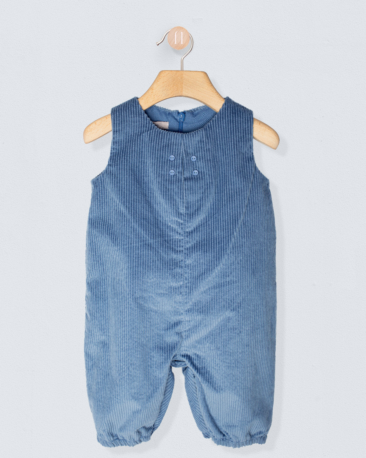 Blue corduroy baby romper on a hanger against a light gray background