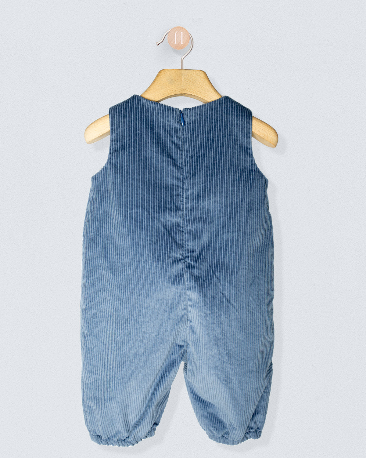 Back of blue corduroy baby romper on a hanger against a light gray background