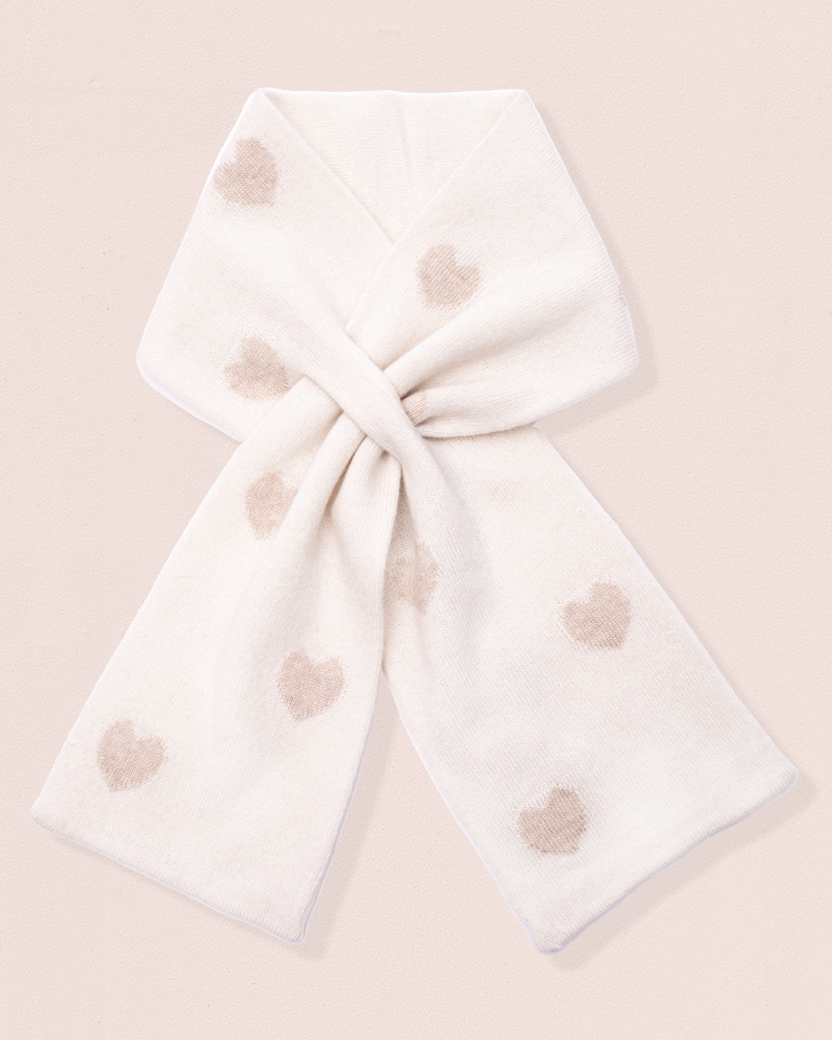 White scarf with gold-hue heart patterns tied on a light pink background