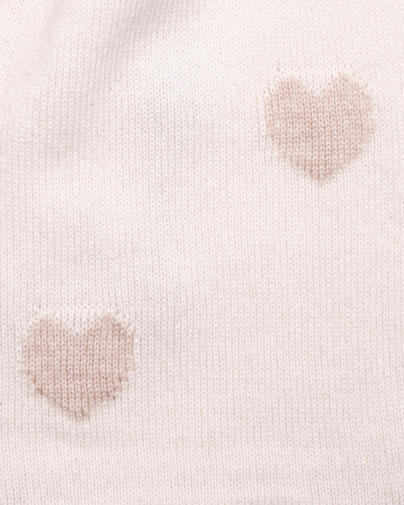 Close-up of a light cream cashmere scarf with gold-hue heart patterns