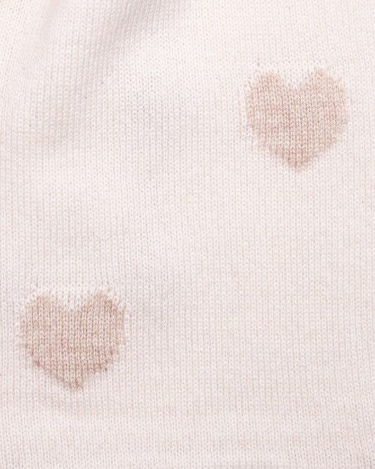 Close-up of a light cream cashmere scarf with gold-hue heart patterns