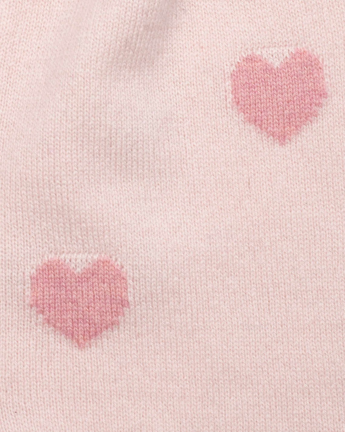 Close-up of pink heart patterns on a light pink fabric background
