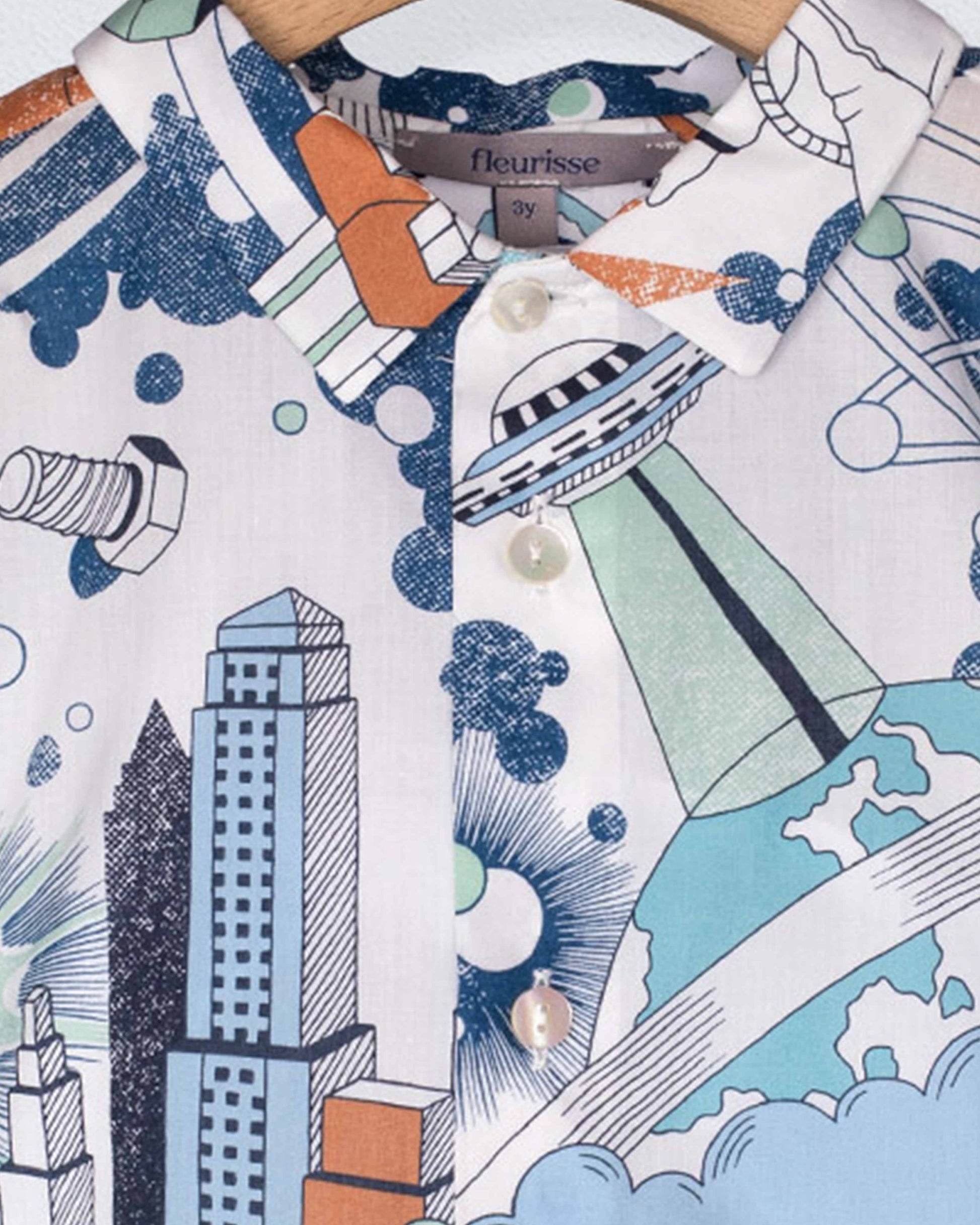 Close-up of a shirt with a colorful abstract design featuring buildings and geometric shapes.