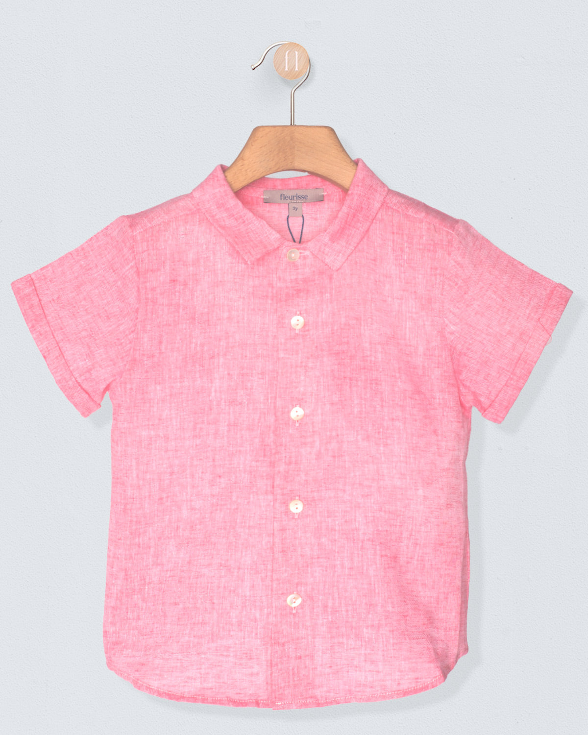 Pink short-sleeve shirt on a hanger against a light gray background