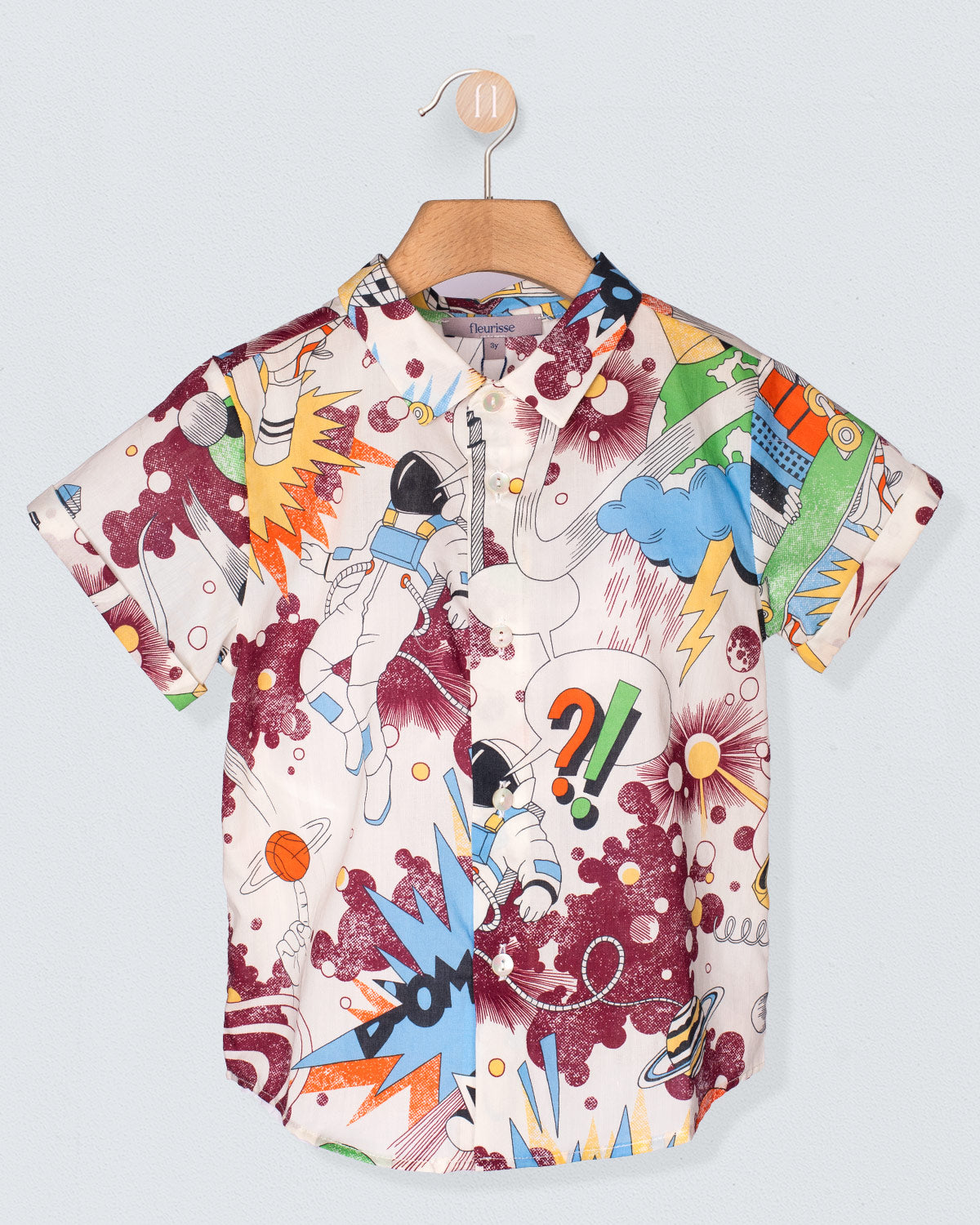 Colorful shirt with abstract designs on a hanger against a light gray background