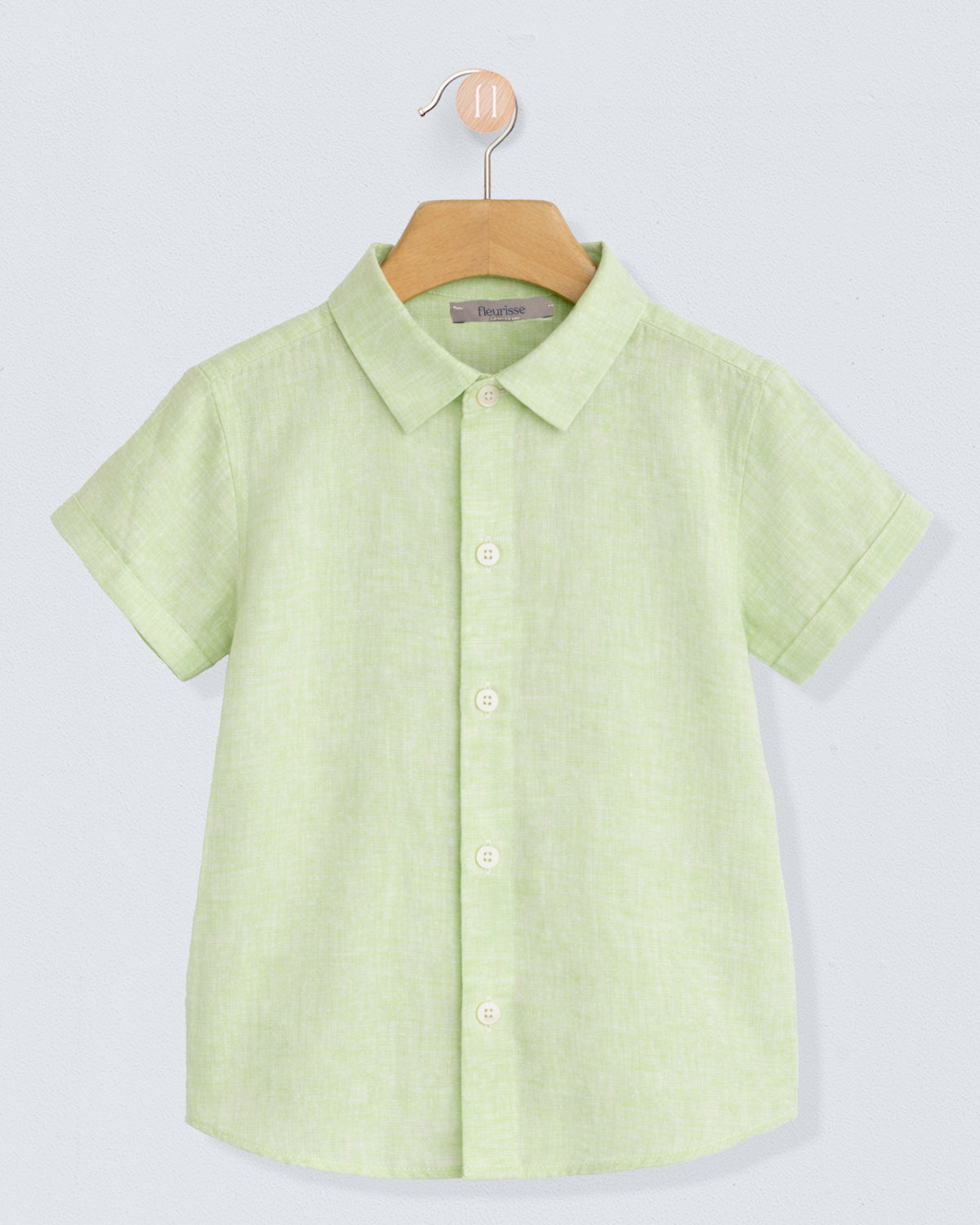 Green shirt on a hanger against a light gray background