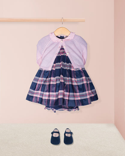 Children's dress with plaid pattern and matching shoes on a pink background