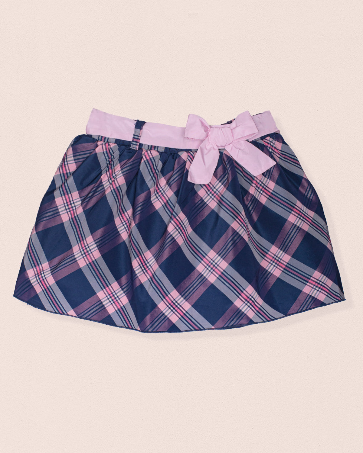 Navy and pink plaid skirt with a bow on a beige background