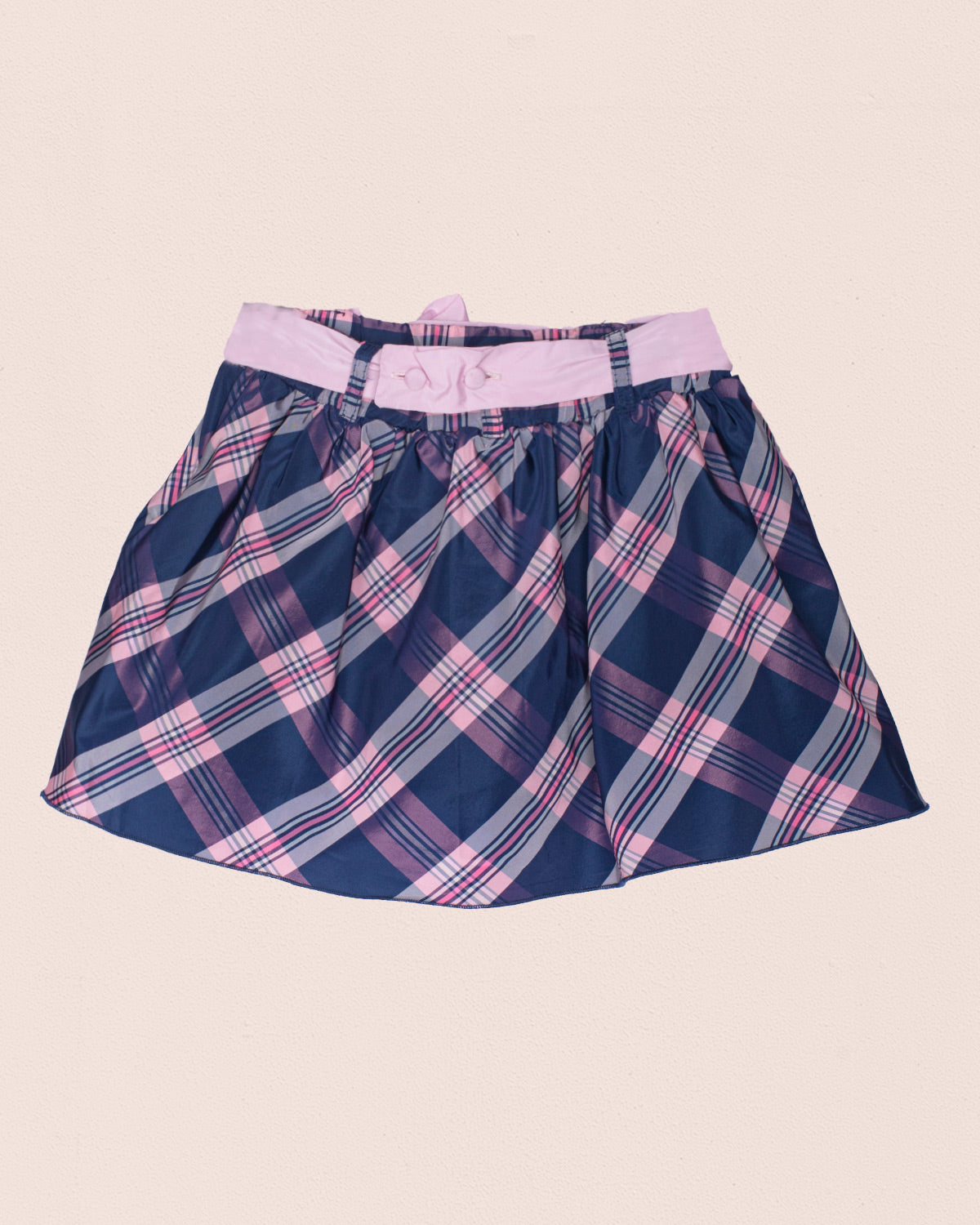 Back of navy blue and pink plaid skirt with pink waistband on a beige background
