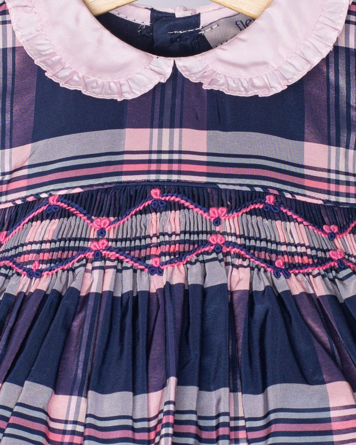 Plaid dress with embroidered details on a hanger