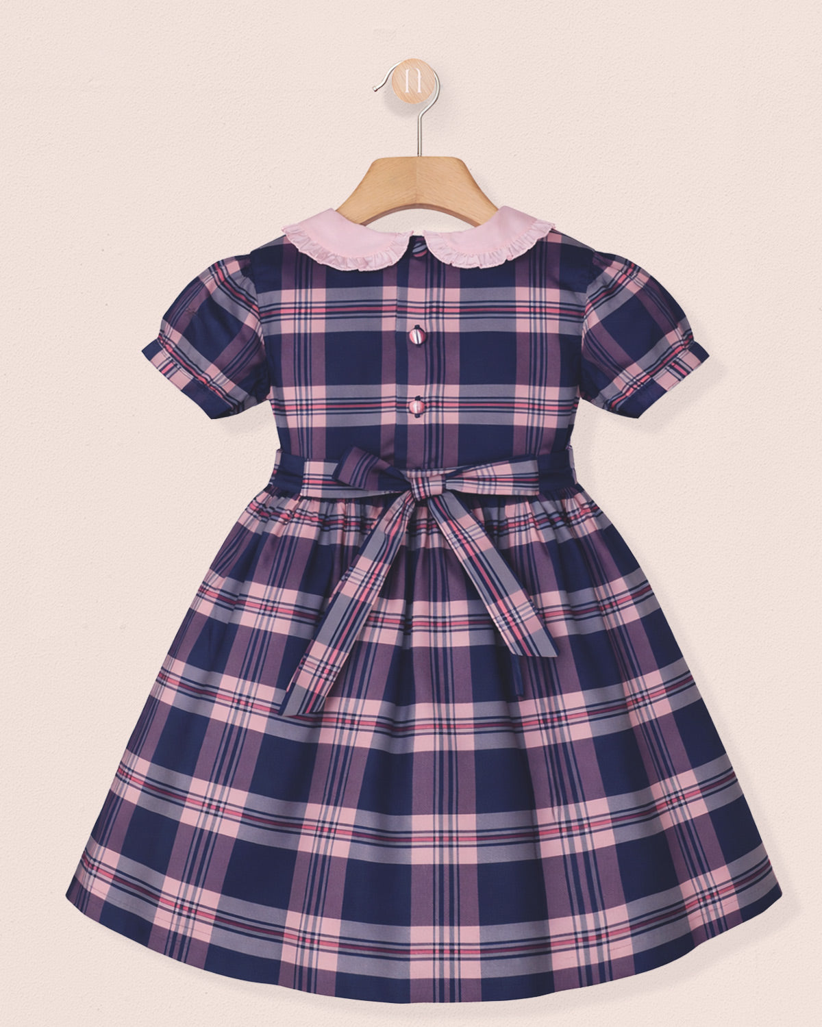 Navy and pink plaid dress with a white collar on a beige background
