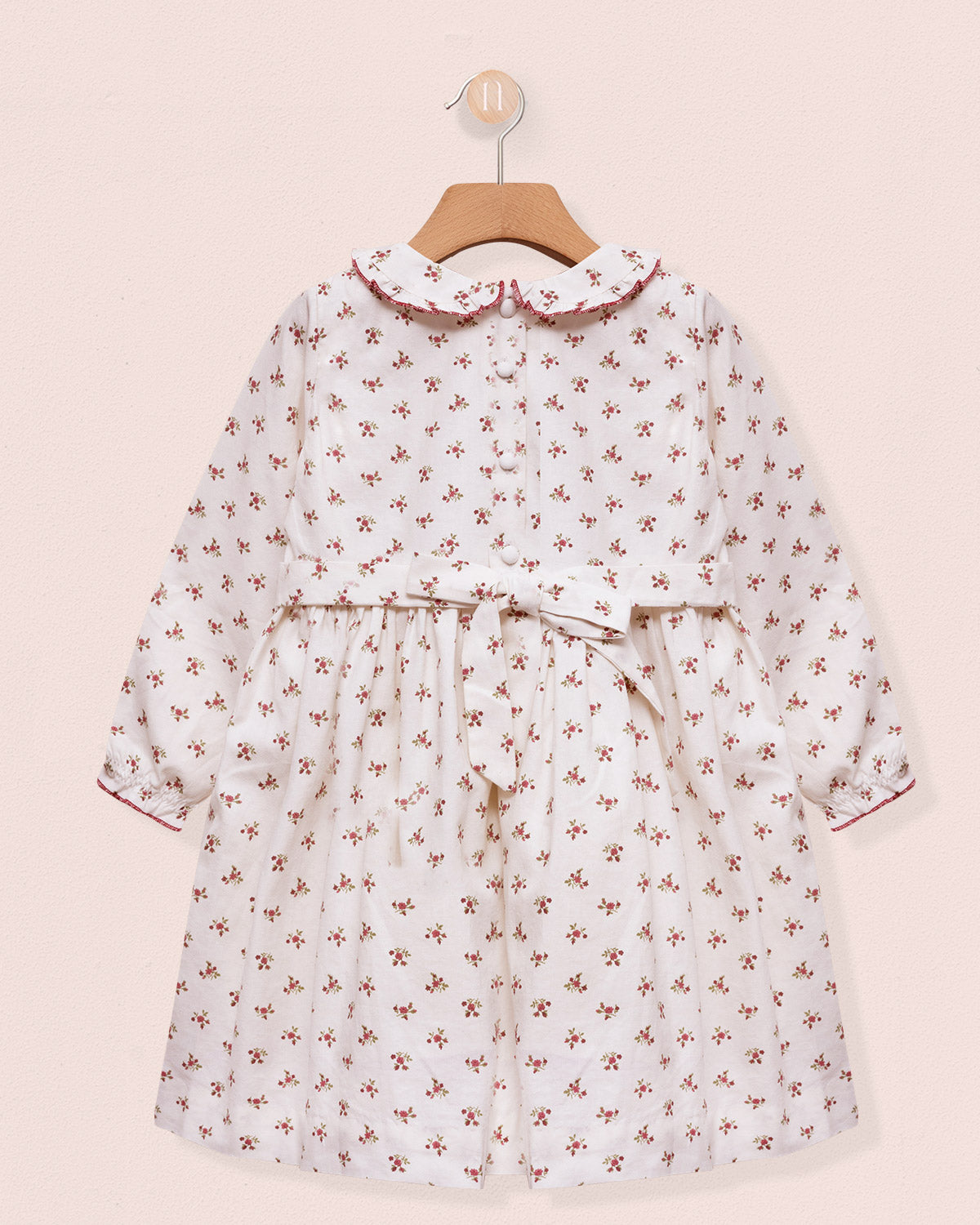 Floral dress on a hanger against a pink background