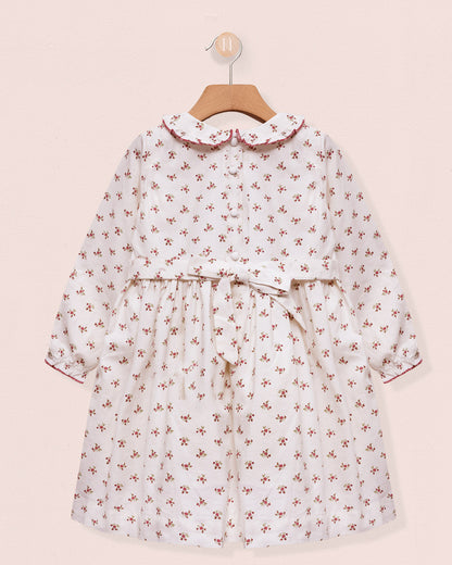 Floral dress on a hanger against a pink background