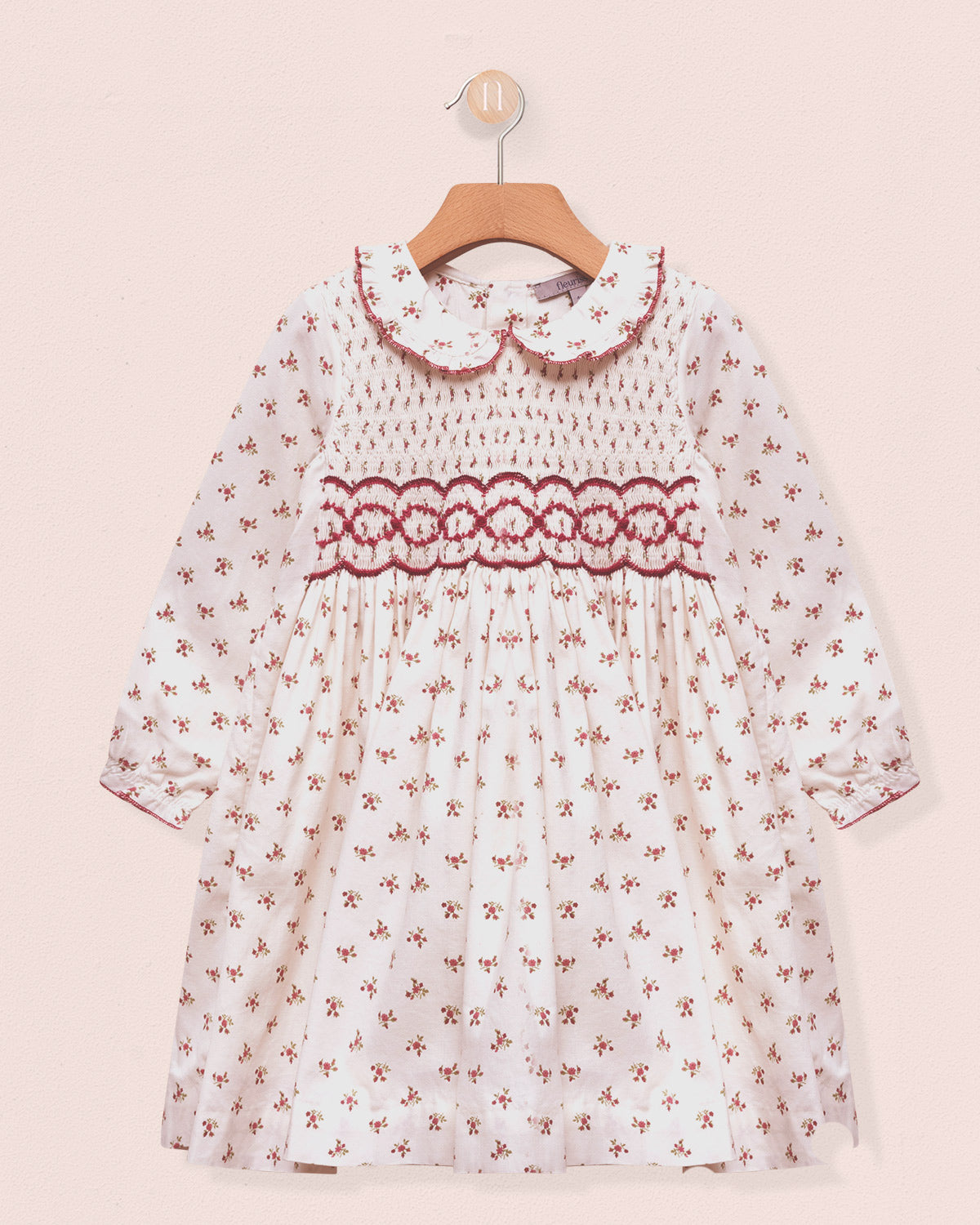 White dress with red floral pattern on a pink background