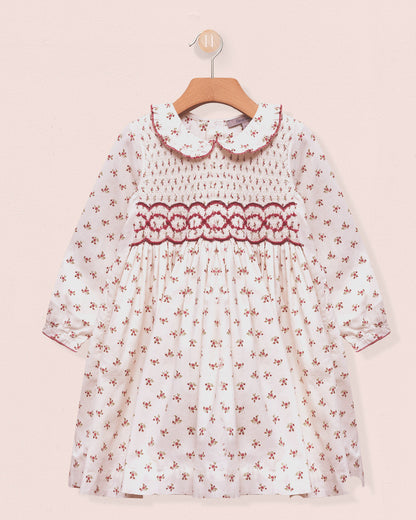 White dress with red floral pattern on a pink background
