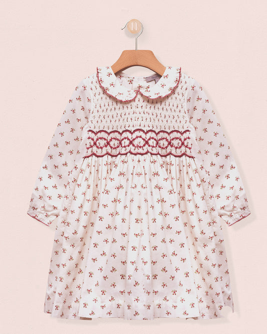 White dress with red floral pattern on a pink background
