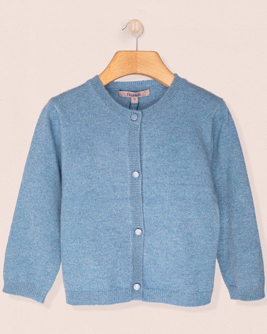 Blue knitted cardigan on a wooden hanger against a beige background