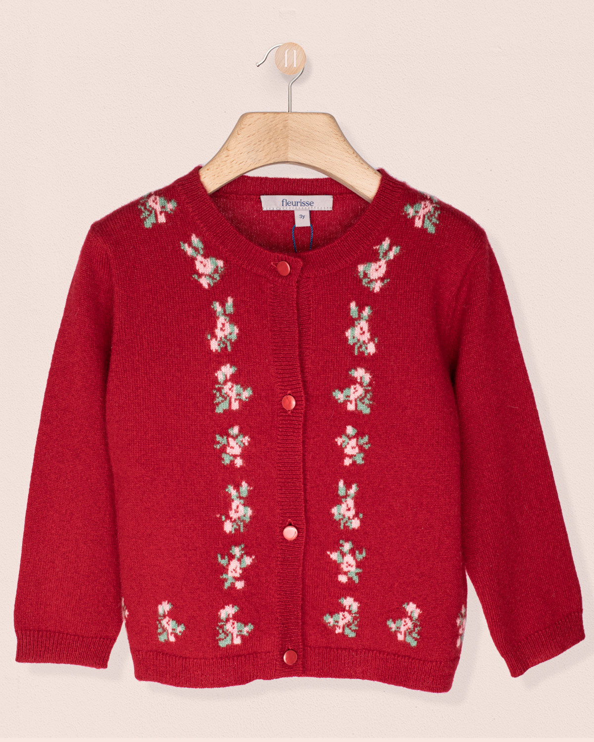 Red cardigan with floral patterns on a beige background