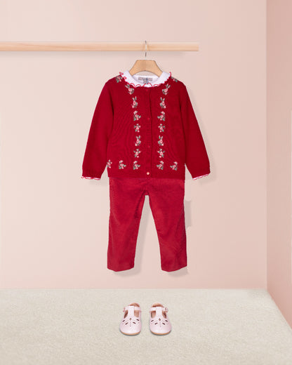 Red children's outfit with floral embroidery on a pink background