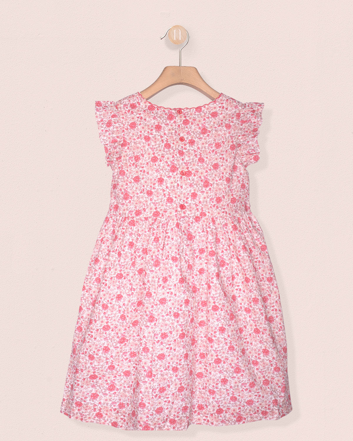 Pink floral dress on a hanger against a light pink background