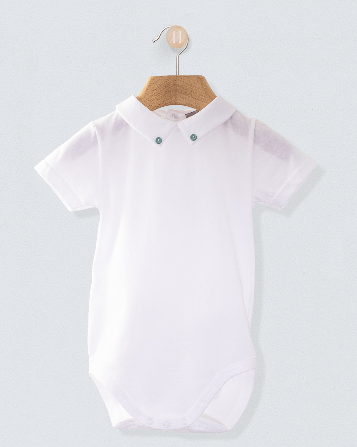 Front view of the Andreas White Onesie with Hunter Buttons, a short-sleeve white cotton jersey onesie with a crisp collar detailed with two small hunter green buttons.