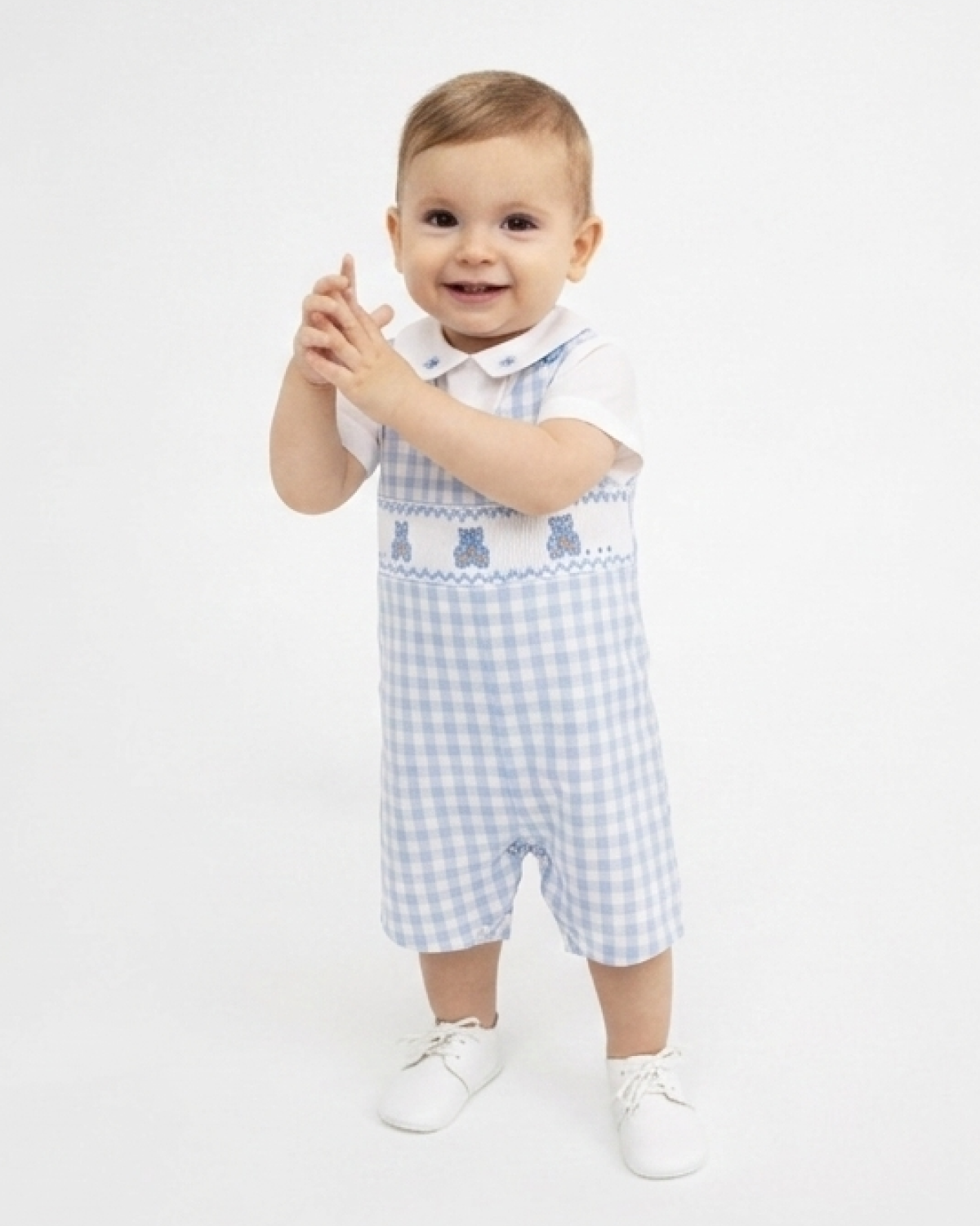 Baby wearing a blue and white checkered outfit with a collar on a white background